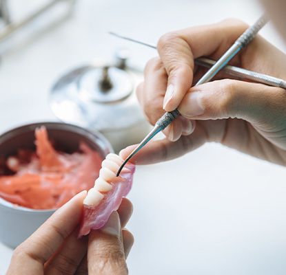 A technician making a denture’s base and artificial teeth