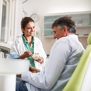 Smiling dentist talking to patient in treatment room